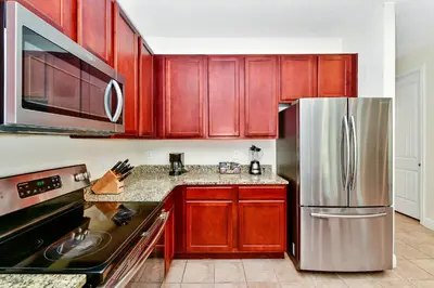 a kitchen with wooden cabinets and a stainless steel refrigerator at Spectacular Home Near Disney With Private Pool And Waterpark & Resort Access At Encore Resorts Reunion - 7523Mr in Kissimmee