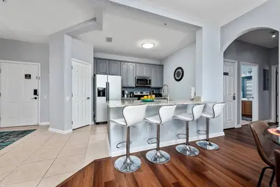an open kitchen and living room with a counter and stools at Vista Cay Resort in Orlando