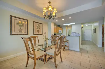 a dining room and kitchen with a glass table and chairs at 1 Mi to Disney Condo with Water-View Balcony! in Orlando