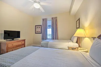 a bedroom with two beds and a flat screen tv at 1 Mi to Disney Condo with Water-View Balcony! in Orlando