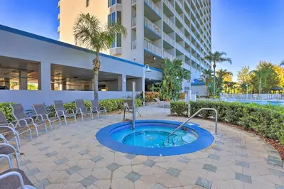 a hot tub in a patio with chairs and a building at 1 Mi to Disney Condo with Water-View Balcony! in Orlando