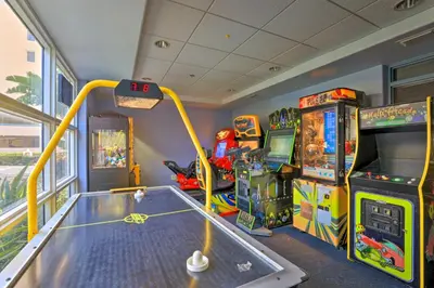 a gaming room with a table and arcade games at 1 Mi to Disney Condo with Water-View Balcony! in Orlando