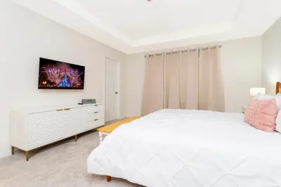 a white bedroom with a bed and a tv on the wall at 1798 TP - 4BR Luxury Solara Retreat Pool Disney in Orlando