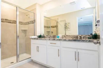 a white bathroom with a shower and a sink at 1798 TP - 4BR Luxury Solara Retreat Pool Disney in Orlando