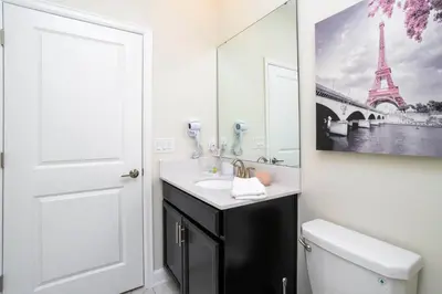 a bathroom with a sink and a toilet and a mirror at 2929 SS - Disney Delight: 4BR Pool Near Parks in Kissimmee