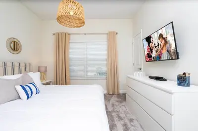 a bedroom with a white bed and a tv on the wall at 2929 SS - Disney Delight: 4BR Pool Near Parks in Kissimmee