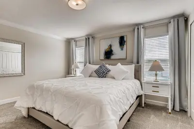 a white bedroom with a bed and two windows at 4321 QS - Magical Haven Townhome w Pool in Kissimmee