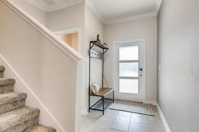 a hallway with white walls and stairs with a chair at 4321 QS - Magical Haven Townhome w Pool in Kissimmee