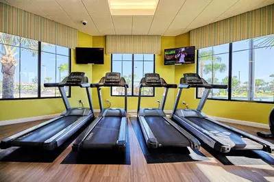 a gym with three treadles in a room with windows at Blue Toucan At Storey Lake By Shine Villas #402 in Kissimmee