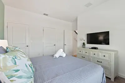a white bedroom with a bed and a television at Blue Beach At Storey Lake By Shine Villas #400 in Kissimmee