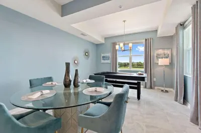 a dining room with a table and chairs and a piano at Decadent Penguin - Storey Lake By Shine Villas #704 in Kissimmee