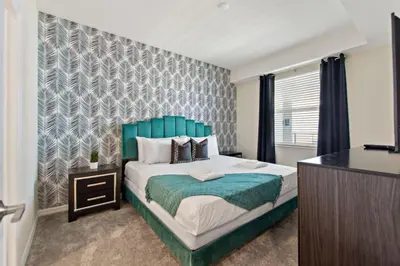 a bedroom with a large bed with a blue headboard at Decadent Penguin - Storey Lake By Shine Villas #704 in Kissimmee