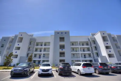 a parking lot with cars parked in front of a building at Decadent Penguin - Storey Lake By Shine Villas #704 in Kissimmee
