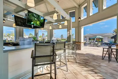 a patio with chairs and a bar with a flat screen tv at Firecracker View Storey Lake By Shine Villas #838 in Kissimmee