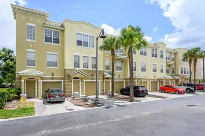 a large yellow building with palm trees in a parking lot at Beautiful Townhome, Vista Cay, Near Parks! 4018 in Orlando