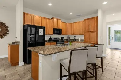 a kitchen with a large island with bar chairs at 350 Pendant · 350 Villa - 8BD - Private Pool - Game room in Orlando