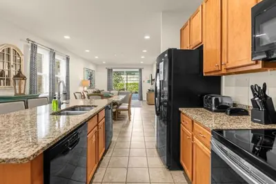 a kitchen with wooden cabinets and a black refrigerator at 350 Pendant · 350 Villa - 8BD - Private Pool - Game room in Orlando