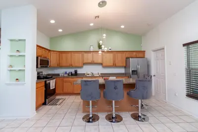 a kitchen with wooden cabinets and blue bar stools at Gorgeous Fully Furnished 2-Bedroom Luxury Villa in Kissimmee