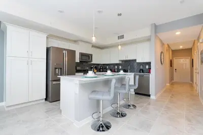 a kitchen with white cabinets and a large island with bar stools at Sweet Suite Sleeps 6 Storey Lake By Shine Villas #903 in Kissimmee