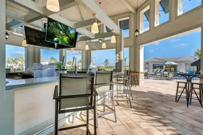a patio with chairs and a bar with a flat screen tv at Edgewater Escape At Storey Lake By Shine Villas #904 in Kissimmee