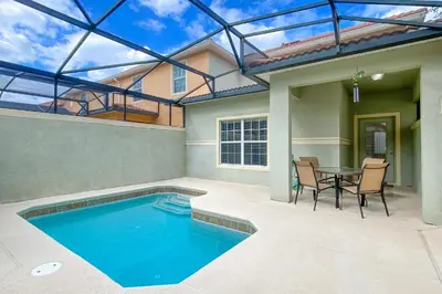a house with a swimming pool and a table and chairs at Mickeys Paradise - a fabulous 4 bed Paradise Palms Resort pool home that's close to Disney in Kissimmee