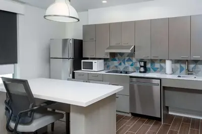a kitchen with a white counter and a table with a chair at Hyatt House Orlando Airport in Orlando