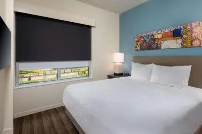 a bedroom with a white bed and a large window at Hyatt House Orlando Airport in Orlando