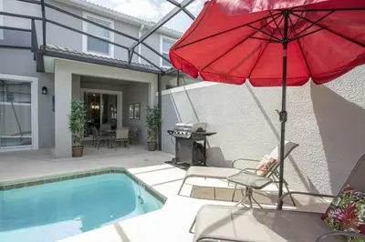 a red umbrella and chairs next to a swimming pool at Amazing Lovely Private Pool 4844 in Kissimmee