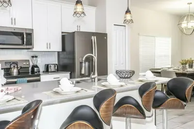 a kitchen with white cabinets and black chairs at Astonishing Home Private Pool 4830 in Kissimmee