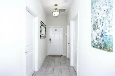 a hallway with white walls and a white door with a painting at Astonishing Home Private Pool 4830 in Kissimmee