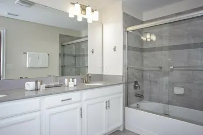 a white bathroom with a shower and a sink at Astonishing Home Private Pool 4830 in Kissimmee