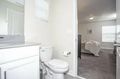 a white bathroom with a toilet and a bedroom at Astonishing Home Private Pool 4830 in Kissimmee