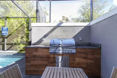a outdoor kitchen with a grill and a pool at Modern 4 bedroom Home Private Pool 4451 in Kissimmee