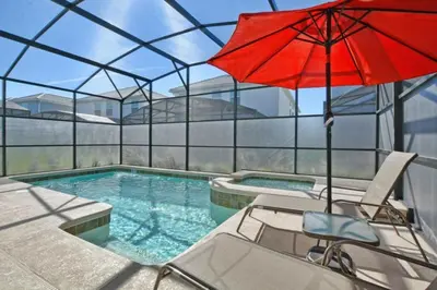 a pool with a red umbrella and a chair and a swimming pool at 4712 Fabulous Brand-New Private Pool in Kissimmee