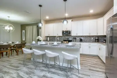 a kitchen with white cabinets and a large island with stools at 4712 Fabulous Brand-New Private Pool in Kissimmee