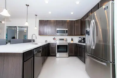 a kitchen with wooden cabinets and a stainless steel refrigerator at 4774 Gorgeous Townhome in Kissimmee