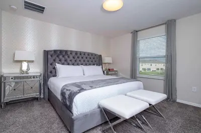 a bedroom with a large bed and two white chairs at 4774 Gorgeous Townhome in Kissimmee