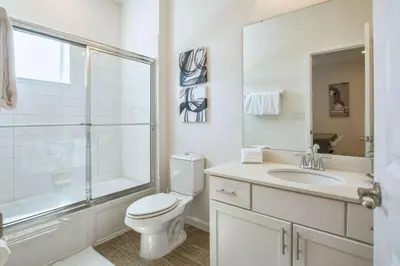 a white bathroom with a toilet and a sink at 2600YA Luxury Gorgeous Private Pool in Kissimmee