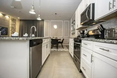 a kitchen with white cabinets and appliances with a table at 2620 Magical Memories 15 min-Disney in Orlando