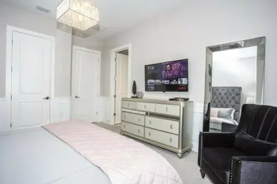 a bedroom with a bed and a mirror and a chair at 2620 Magical Memories 15 min-Disney in Orlando
