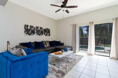 a living room with a blue couch and a ceiling fan at Cozy 3 bedroom home with Private Pool 4564 in Kissimmee