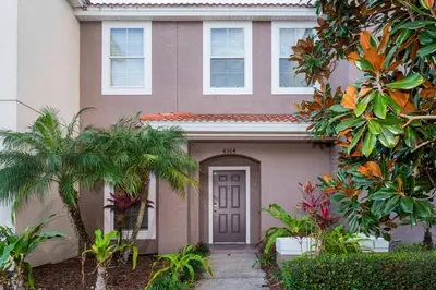 a house with a door and palm trees in front of it at Cozy 3 bedroom home with Private Pool 4564 in Kissimmee