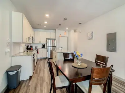 a kitchen with a table and chairs and a kitchen with white cabinets at Large Apartment, Close To Disney in Kissimmee