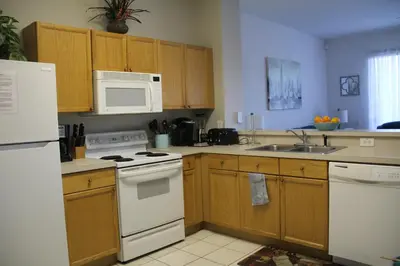 a kitchen with white appliances and wooden cabinets at Veteran Owned 3bdr/3 bath Townhouse w/WiFi 3mi to Disney - Fall/Winter Specials in Kissimmee