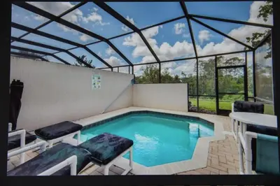 a swimming pool in a glass house with a table and chairs at Veteran Owned 3bdr/3 bath Townhouse w/WiFi 3mi to Disney - Fall/Winter Specials in Kissimmee