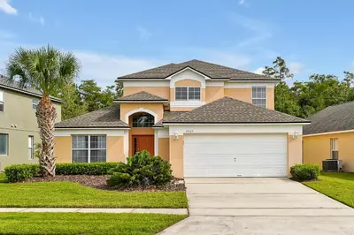 a house with a white garage in a yard at Walkin' on Sunshine - 5 bed pool home in Terra Verde Resort near Disney in Kissimmee