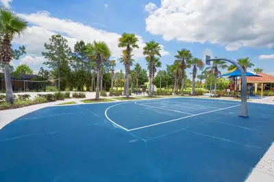 a tennis court with palm trees and a basketball hoop at Walkin' on Sunshine - 5 bed pool home in Terra Verde Resort near Disney in Kissimmee