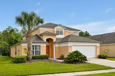a house with a palm tree in front of it at Walkin' on Sunshine - 5 bed pool home in Terra Verde Resort near Disney in Kissimmee