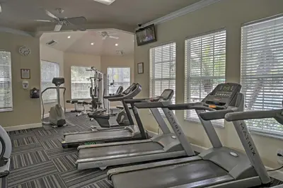 a gym with several tread machines in a room with windows at 6 Mi to Disney World Condo with Community Perks! in Kissimmee