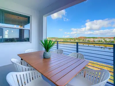 a wooden table and white chairs on a balcony at Gorgeous 2BR lakeview Condo with Waterpark in Kissimmee